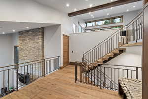 Staircase featuring hardwood / wood-style flooring, recessed lighting, beam ceiling, and a high ceiling