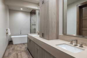Full bath featuring double vanity, a freestanding tub, dark wood-type flooring, recessed lighting, and a shower stall