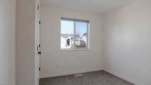 Carpeted spare room featuring baseboards