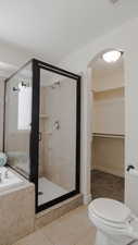 Bathroom featuring a shower stall, light tile patterned floors, a bath, and a walk in closet