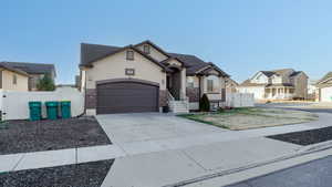 View of front of property featuring a gate, stucco siding, driveway, and brick siding