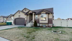 View of front facade with a gate, stucco siding, concrete driveway, brick siding, and an attached garage