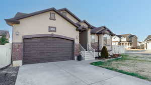 View of front of house featuring stucco siding, driveway, brick siding, and an attached garage