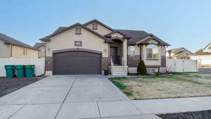 View of front of property featuring stucco siding, a gate, concrete driveway, an attached garage, and brick siding