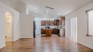 Kitchen with pendant lighting, a kitchen island, arched walkways, dark wood-style floors, and recessed lighting