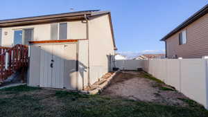 View of property exterior with a fenced backyard, a gate, and a storage unit