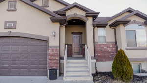 View of exterior entry with stucco siding and brick siding