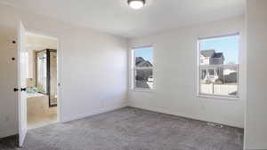 Unfurnished bedroom featuring light colored carpet and connected bathroom
