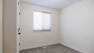 Carpeted spare room featuring baseboards
