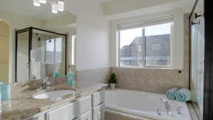 Full bathroom featuring a bath, vanity, and a stall shower