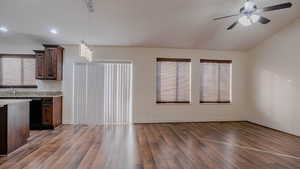 Kitchen with dark wood-type flooring, hanging light fixtures, dark brown cabinetry, light stone counters, and ceiling fan