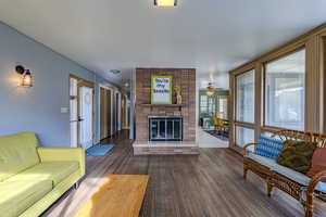 Living area with dark wood-style flooring, a fireplace, and ceiling fan