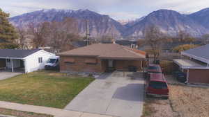 Ranch-style house featuring concrete driveway, brick siding, a carport, and roof with shingles