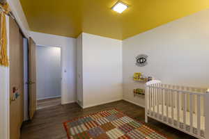 Bedroom with a nursery area and dark wood finished floors