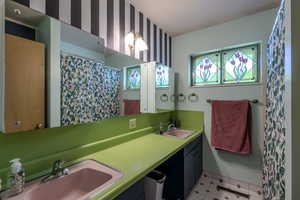 Bathroom with wallpapered walls, double vanity, and a shower with shower curtain