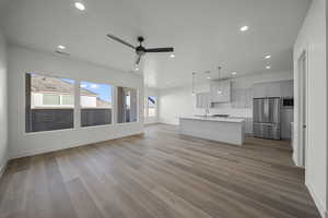 Unfurnished living room featuring a ceiling fan, recessed lighting, and dark wood-style flooring