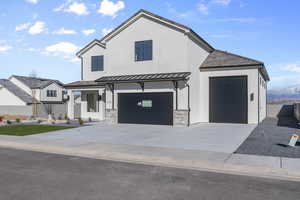View of front facade featuring stucco siding, concrete driveway, a standing seam roof, and a metal roof