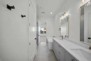 Full bathroom featuring a freestanding tub, double vanity, and recessed lighting