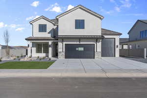 View of front of home with stucco siding, a standing seam roof, concrete driveway, an attached garage, and a metal roof