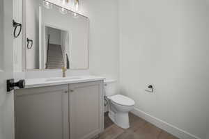 Half bathroom featuring vanity and dark wood-style flooring