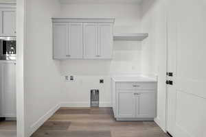 Laundry room featuring hookup for an electric dryer, light wood-type flooring, washer hookup, and cabinet space