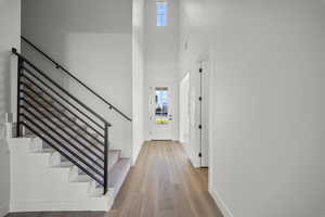 Entrance foyer featuring a high ceiling, light wood finished floors, and stairway