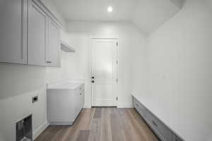 Washroom with light wood-type flooring, cabinet space, lofted ceiling, electric dryer hookup, and recessed lighting