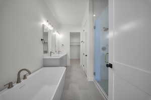 Full bath featuring a stall shower, a freestanding tub, vanity, and a walk in closet