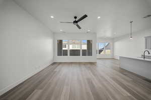 Unfurnished living room with light wood-style floors, recessed lighting, a ceiling fan, and vaulted ceiling