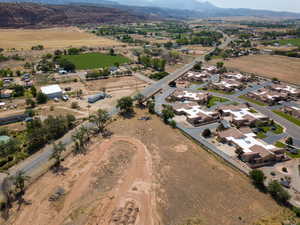Aerial view of property and surrounding area featuring a mountainous background, rural landscape, and nearby suburban area