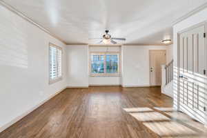 Empty room featuring hardwood / wood-style flooring, crown molding, ceiling fan, and stairs