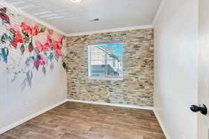 Empty room with wood finished floors and crown molding