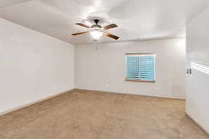 Empty room with light carpet, ceiling fan, and a textured ceiling