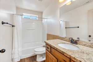 Bathroom featuring vanity, shower / tub combo, and dark wood-style floors