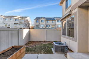 Fenced backyard featuring a vegetable garden, a residential view, and a patio