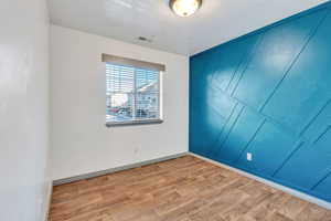 Unfurnished bedroom with light wood finished floors and a decorative wall