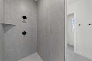 Full bathroom featuring a tile shower and baseboards