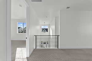 Corridor with light colored carpet and baseboards
