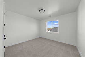 Empty room with light colored carpet and baseboards