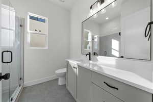 Full bath with a shower stall, vanity, and light tile patterned flooring