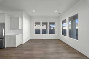 Unfurnished dining area featuring dark wood-style flooring and recessed lighting