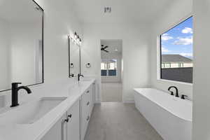 Bathroom featuring a soaking tub, double vanity, a ceiling fan, and light carpet