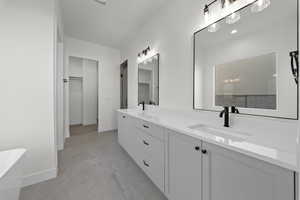 Bathroom featuring double vanity, a freestanding bath, and a spacious closet