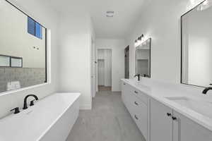 Full bathroom with a freestanding bath, double vanity, a spacious closet, and light marble finish flooring