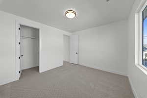 Unfurnished bedroom featuring light colored carpet and a walk in closet
