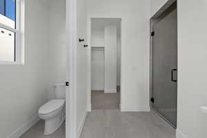 Bathroom featuring a shower stall and a walk in closet