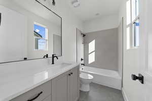 Bathroom with shower / tub combination, vanity, and dark tile patterned flooring
