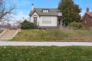 Tudor house featuring stucco siding, a front lawn, a chimney, and a shingled roof