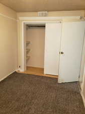 Unfurnished bedroom with light carpet, a closet, and a textured ceiling