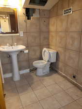 Half bathroom with tile walls and light tile patterned flooring